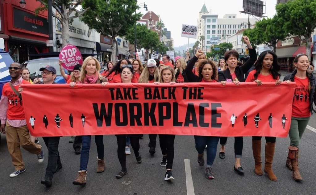 Protesters holding a banner that says "Take Back the Workplace."