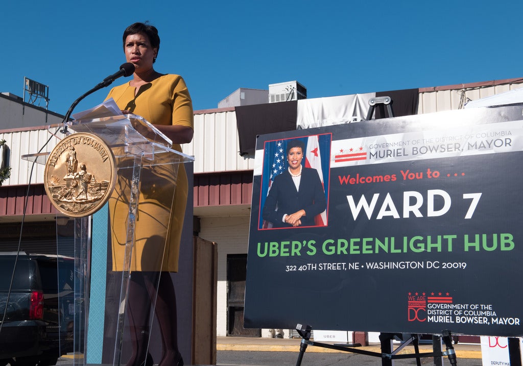 D.C. mayor Muriel Bowser stands in front of a podium. Next to her, a sign says 