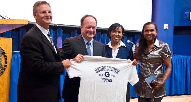John DeGoia holding a Georgetown shirt with three other people.